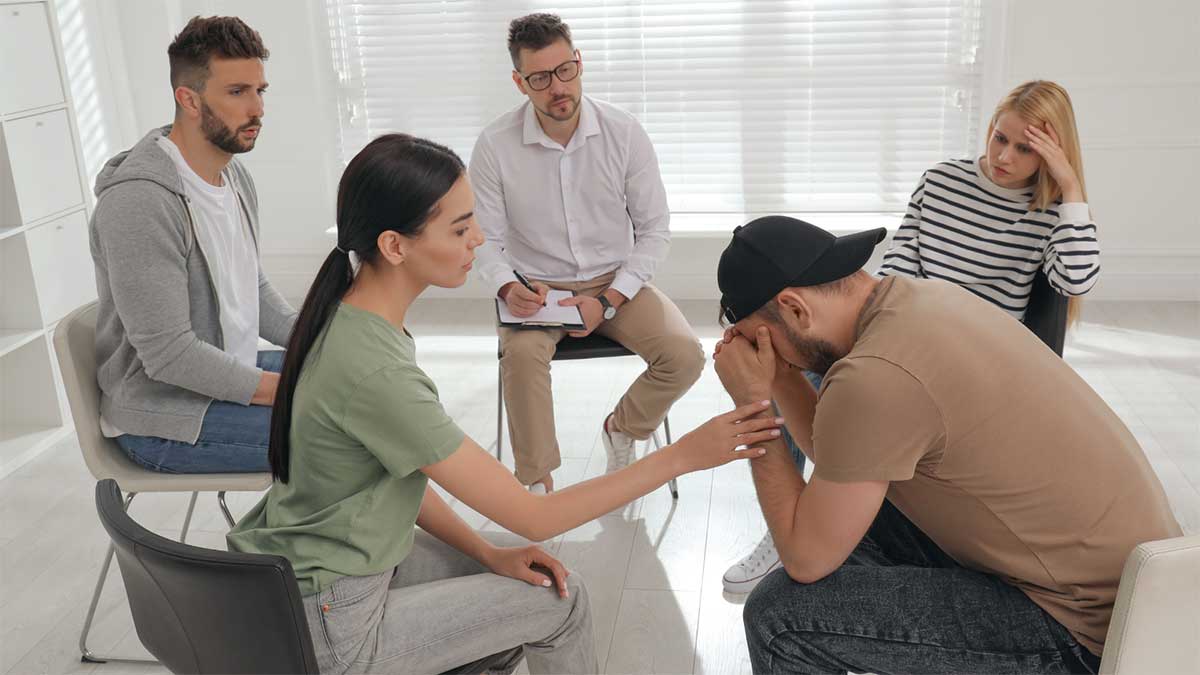 A therapy session where a group of people console a single patient