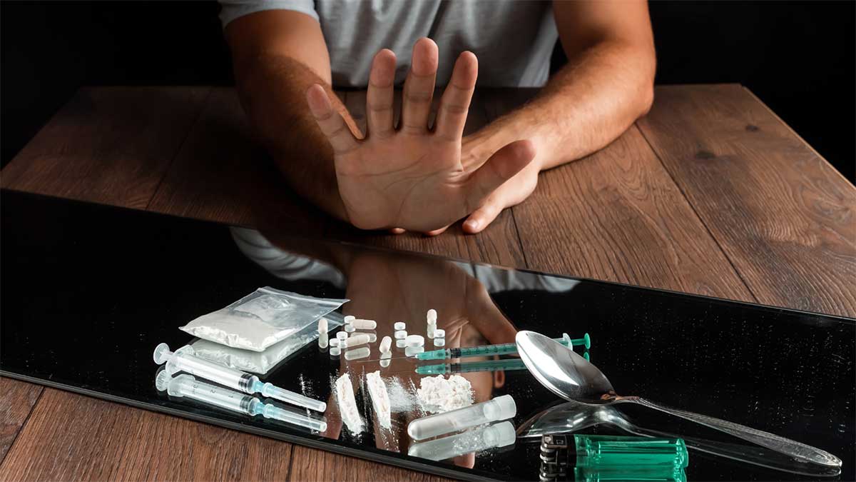 Person rejecting drugs with an outstretched hand over drug paraphernalia