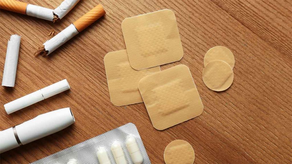 Nicotine patches and broken cigarettes on a wooden surface.