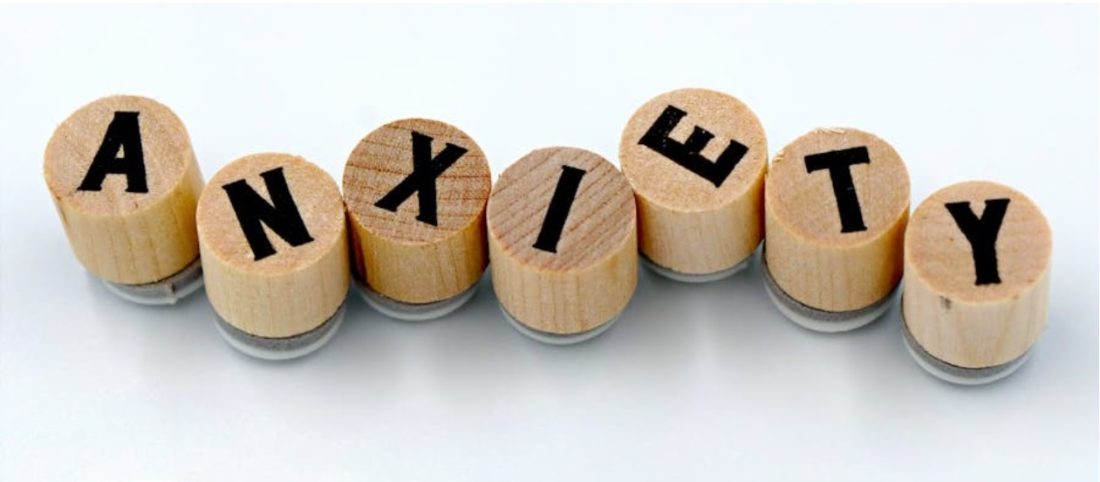 Wooden stamps with black letters spell out the word "ANXIETY" against a plain white background.