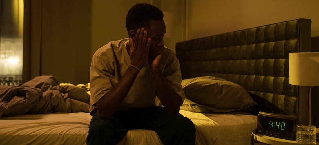A person sitting on a bed late at night, struggling with anxiety and alcohol effects
