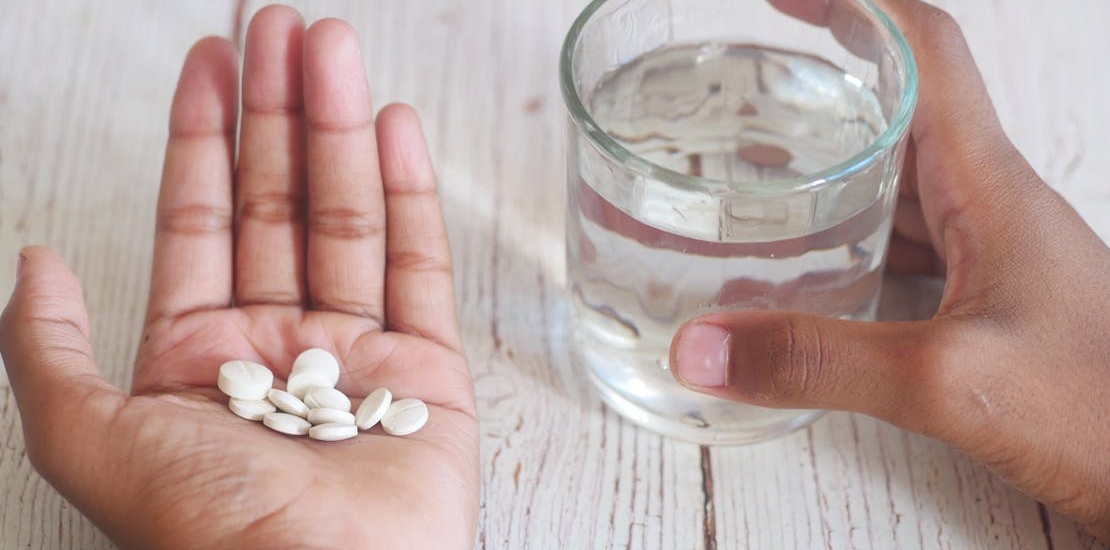 a person holding water and white pills wondering do mood stabilizers help with anxiety.